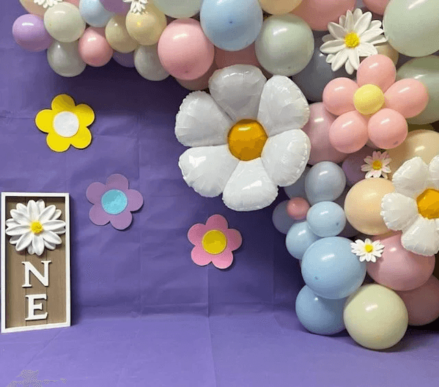 Instalación de globos pastel estilo boho con margaritas para un primer cumpleaños